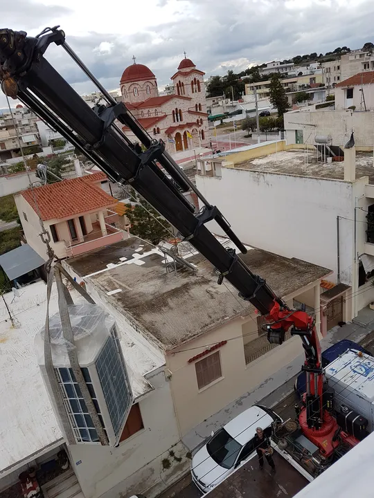 Ανυψωτικό μηχάνημα σε εργασία εγκατάστασης δίπλα σε κτίριο